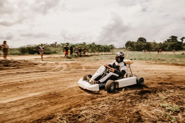 Driver taking a turn in a dirt go-kart