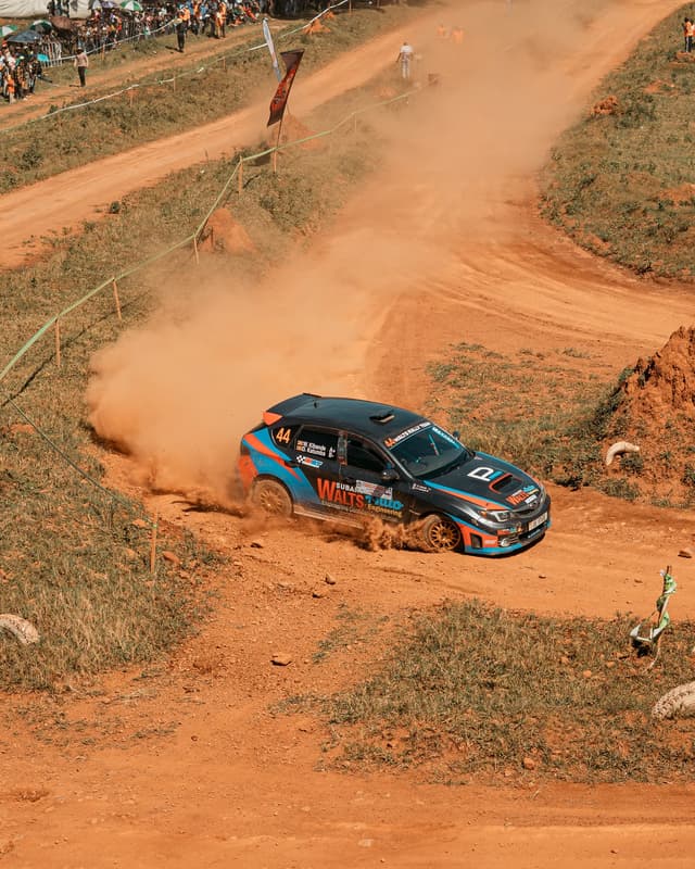 Rally car drifting through a dusty corner at Garuga